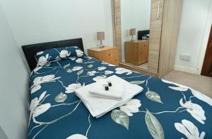 a bedroom with a bed with a blue blanket with flowers at Smithy Cottage in Heysham