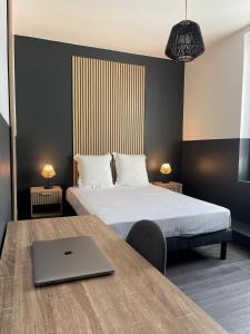 a bedroom with a bed and a laptop on a table at L'Intemporel in Clermont-Ferrand