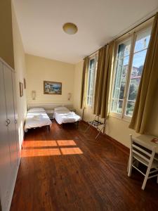 オスペダレッティにあるHotel Petit Royalのベッド2台と窓2つが備わる客室です。
