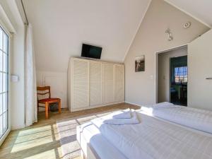 a bedroom with two beds and a tv on the wall at Sturmfrei in Greetsiel