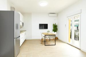 a white kitchen with a table and a refrigerator at Altozano la Victoria D in Andújar