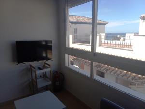 Zimmer mit 2 Fenstern, einem TV und einem Balkon in der Unterkunft Apartamento de 1 dormitorio en Calle Vela in Benalmádena