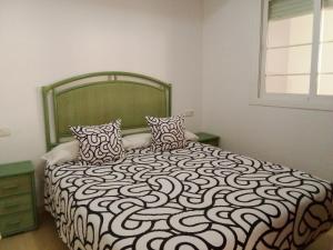 Schlafzimmer mit einem Bett mit einer schwarzen und weißen Bettdecke in der Unterkunft Apartamento de 1 dormitorio en Calle Vela in Benalmádena + 37 Fotos