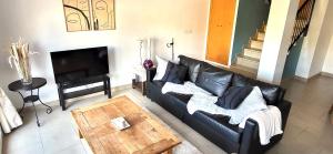 a living room with a black leather couch and a table at Casa Londi in Almuñécar