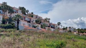 a building on the side of a hill with palm trees at Casa Londi in Almuñécar