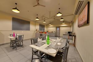 a dining room with a table and chairs and a kitchen at Iris Beacon Hotel in Rajkot