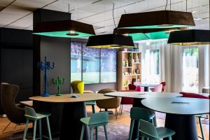 un grupo de mesas y sillas en una habitación en Hotel Novotel Evry Courcouronnes, en Courcouronnes