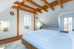 a large white bedroom with a large bed with wooden beams at Käpt'ns Hus in Ahrenshoop
