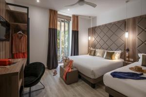 a hotel room with two beds and a chair at GOLDEN TULIP CANNES HOTEL de PARIS in Cannes