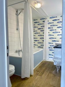 e bagno con vasca, servizi igienici e tenda per la doccia. di Maison ardennaise à Corbion-sur-Semois a Bouillon