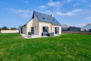 a white house with a black roof on a green field at Maison pour 6 avec jardin à 500 m de la plage in Lilia