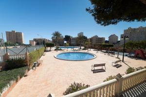 un patio con una piscina con bancos y una valla en Apt Urb Las Lanzas with pool and beach, en La Venteta