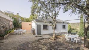 a patio with white tables and chairs and a tree at Casa Rural Río Cedena in Hontanar