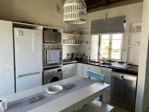a kitchen with a refrigerator and a table in it at Shoreline Cottage in Struisbaai
