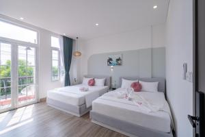 a white room with two beds and a window at Osen Hotel - Grand World Phu Quoc in Phú Quốc