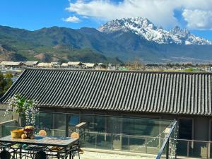 una mesa en un balcón con una montaña en el fondo en Luyu Shijian B&B, en Lijiang