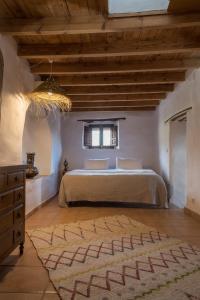 a bedroom with a bed in a room with wooden ceilings at Casa Walhalla & Cortijo El Páramo in Pampaneira