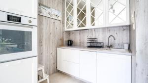 a white kitchen with white cabinets and a sink at Nad Zalewem, Sun & Snow in Dziwnówek