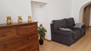 a living room with a grey couch and a dresser at Casa das Amas do Cardeal in Évora