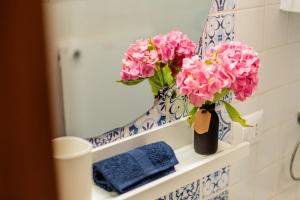 La salle de bains est pourvue d'un vase avec des fleurs roses sur une étagère. dans l'établissement Ortensia Lake View Studio, à Oria 19 autres photos