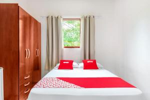 a bedroom with a bed with two red pillows at OYO Pousada Tia Léo Campinas in Campinas