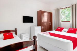 a bedroom with two beds with red pillows at OYO Pousada Tia Léo Campinas in Campinas