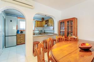 eine Küche und ein Esszimmer mit einem Holztisch und Stühlen in der Unterkunft Bungalow Urb Costa Hispania in Santa Pola