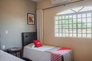 a bedroom with a bed with a red box on it at OYO M&J Hotel in Santo Antônio do Descoberto