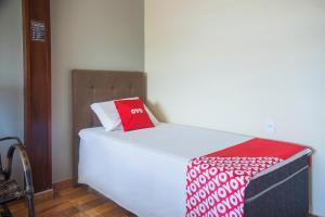 a bed with a red and white pillow on it at OYO M&J Hotel in Santo Antônio do Descoberto