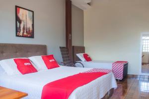 a bedroom with two beds with red and white pillows at OYO M&J Hotel in Santo Antônio do Descoberto