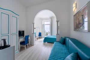 a living room with a blue couch and a bed at Hotel Fontana in Amalfi