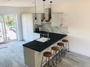 eine Küche mit einer schwarzen Arbeitsplatte und Barhockern in der Unterkunft Stylish 3-Bed Executive Home Chislehurst, BR7 in Chislehurst