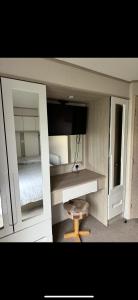 a room with a bed and a desk and a mirror at PG177 Golden Palm Resort 8 Berth Caravan With Decking in Chapel Saint Leonards