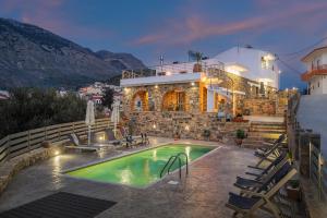 a villa with a swimming pool in front of a house at Zaros Springs Villa Avli in Zaros