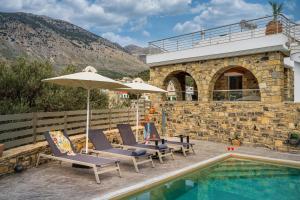a group of chairs and an umbrella next to a pool at Zaros Springs Villa Avli in Zarós