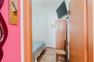 una camera con una parete rosa e una porta con una TV di Casa Chiocciola a San Vito lo Capo