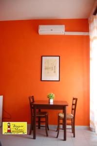 サレルノにあるStanze sul Mareのオレンジ色の壁の客室で、テーブルと椅子が備わります。