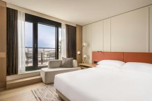 a bedroom with a bed and a chair and a large window at Munich Marriott Hotel City West in Munich