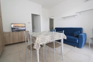a dining room with a table and chairs and a blue couch at Regina Mare in Lido degli Scacchi