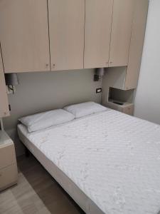 a bedroom with a bed with white sheets and cabinets at Casa Gioia in Peschici