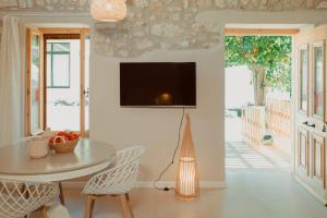 ein Wohnzimmer mit einem Tisch und einem TV an der Wand in der Unterkunft Coastal Cottage Chic House in Vlikhón