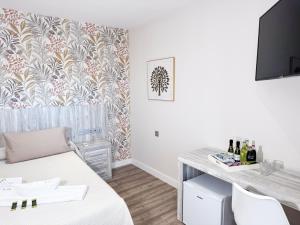 Habitación con escritorio y mesa con botellas de vino. en Hotel Boutique Aroma de Mar, en Chiclana de la Frontera
