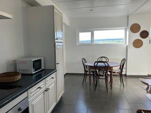 a kitchen with a table with chairs and a microwave at Ocalm gîte B-2h wellness par nuitée à réserver in Libramont