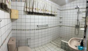 Spacious 4-Bedroom Family Home في باراماريبو: حمام من البلاط الأبيض مع مرحاض ومغسلة