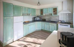 a green kitchen with white appliances and blue cabinets at 3 Bedroom Stunning Home In Plougasnou in Plougasnou +14 photos