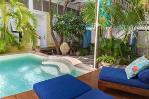 a swimming pool in a yard with palm trees at Plantation House Trinidad suite in Playa del Carmen