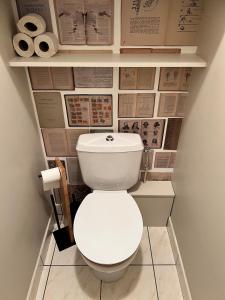 - des toilettes blanches dans une salle de bains avec du papier peint dans l'établissement Carnac joli appartement entre plage et ville!, à Carnac 13 autres photos