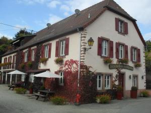 a white building with red shutters at Hôtel du Haut Koenigsbourg- entre vignes et château in Thannenkirch