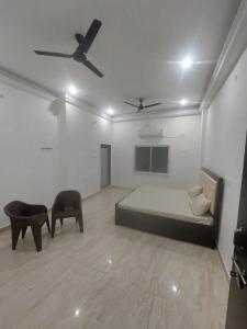 Una habitación con una cama y dos sillas. en Anuj Palace, en Ayodhya