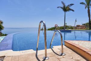 a swimming pool with two metal rails next to the water at Casa Londi in Almuñécar